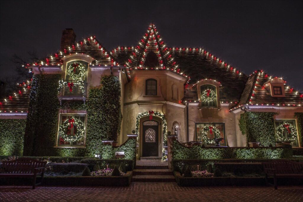 house outlined with red and white christmas lights with wreath and garland